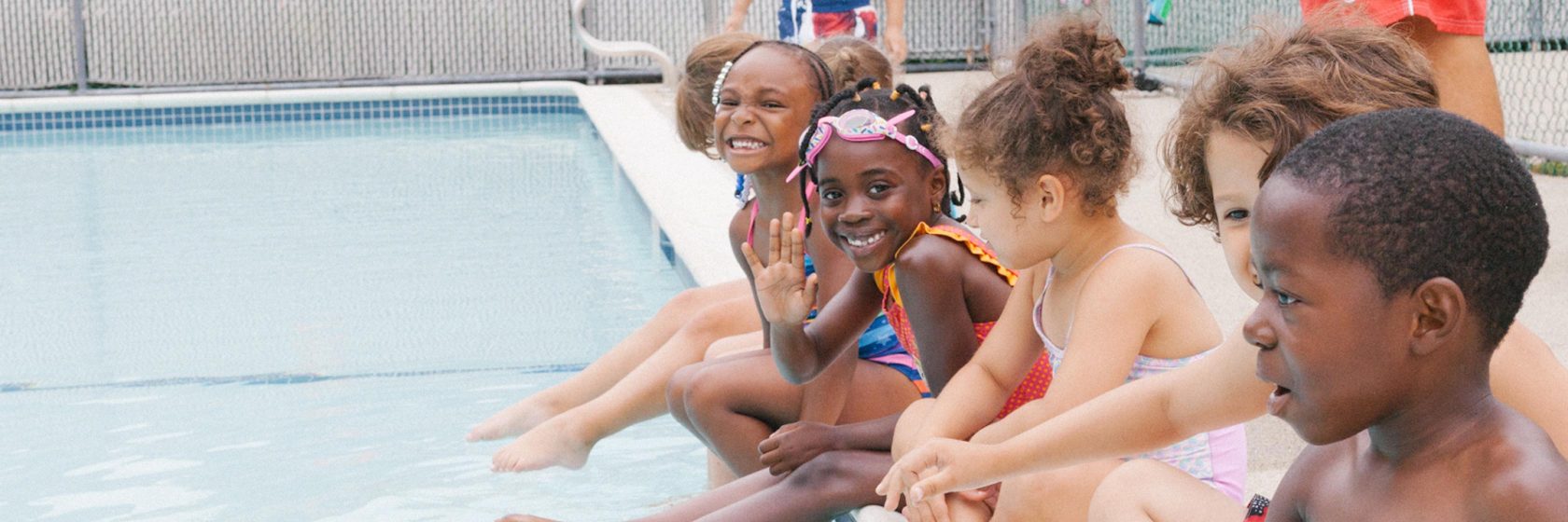 Students sitting at the edge of a pool.