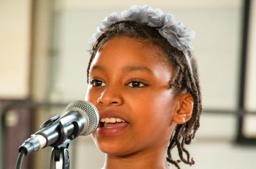 A second grader speaking into a microphone.