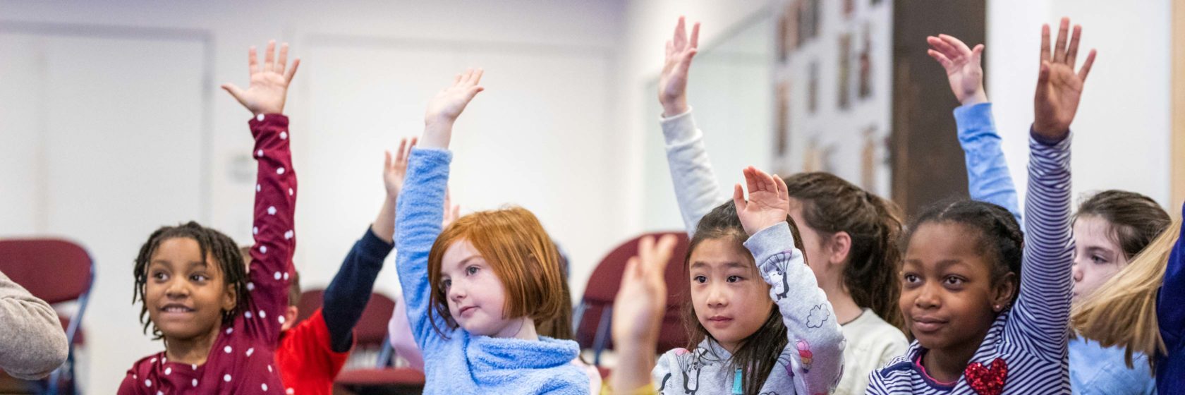 Students raising their hand in a classroom